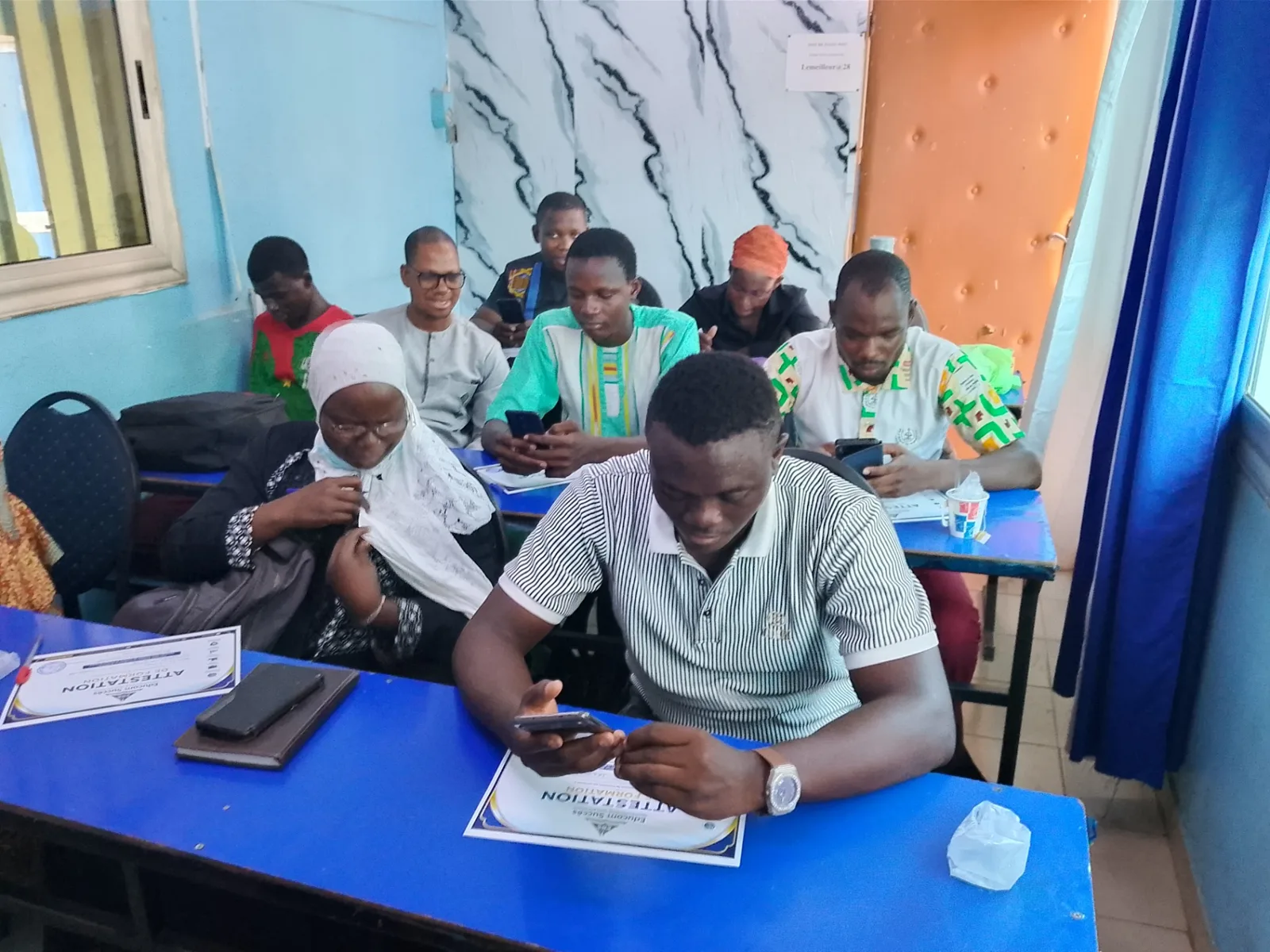 Participants concentrés sur leurs téléphones lors d’une session pratique Educom Succès