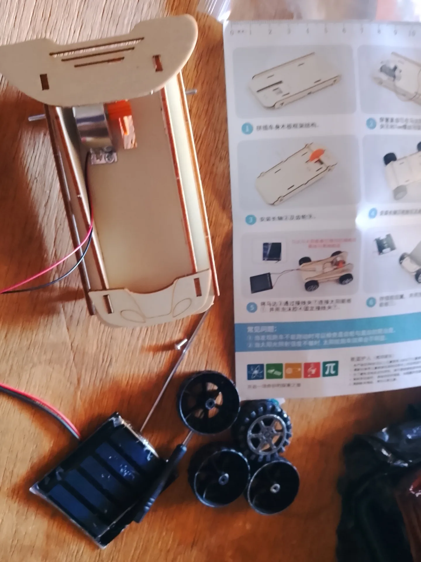 Montage du jouet éducatif suivant la notice, pièces et panneau solaire disposés sur une table