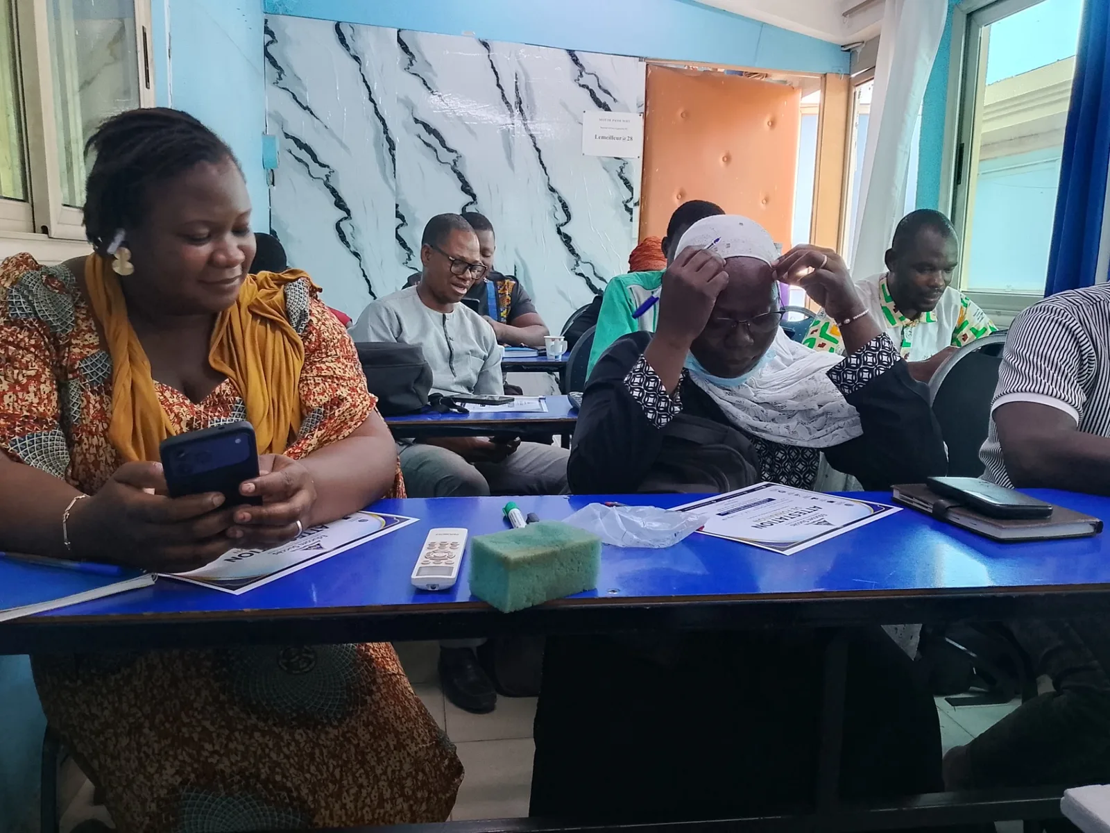 Apprenants en salle travaillant sur smartphone pendant un atelier de création de contenus